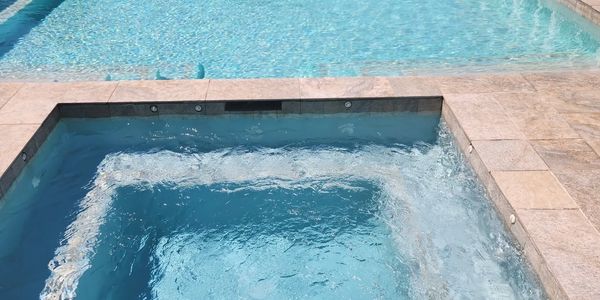 A beuitful pool and spa combo with the jets in the spa pushing water.