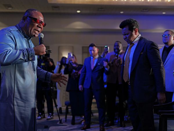 A man passionately speaks into a microphone at an indoor event with a captivated audience.