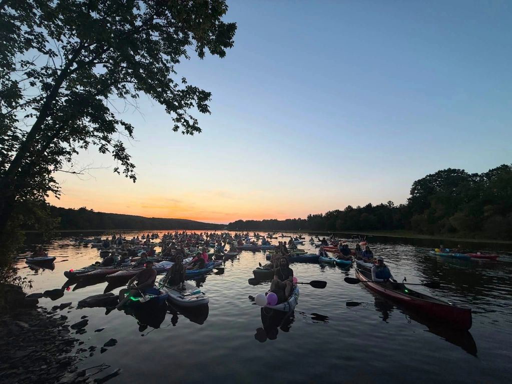Group of kayakers on calm water at sunset.