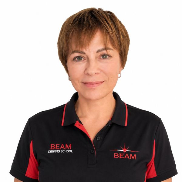 Woman wearing a BEAM Driving School uniform with a friendly expression.