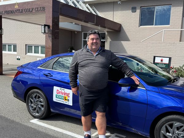 Man standing next to a blue driving school car outside a golf club.