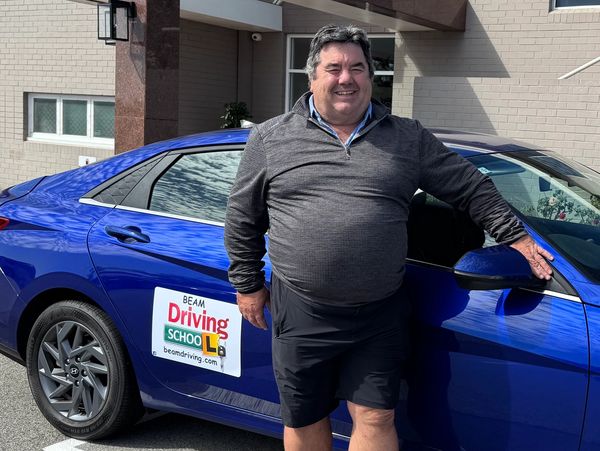 Driving instructor standing next to a driving school car in Fremantle 