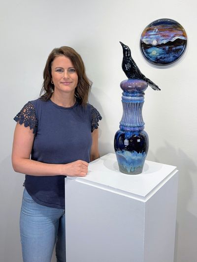 Woman posing with a ceramic sculpture of a bird.