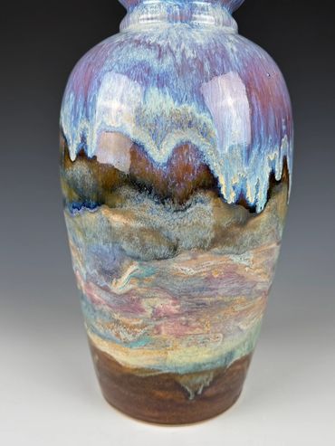 A ceramic vase with a multicolored, textured glaze resembling a natural landscape.
