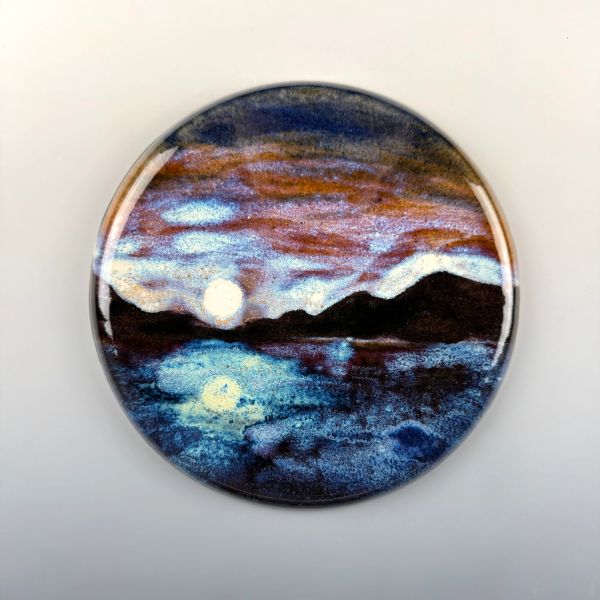Round artwork showing a moonlit lake with mountains under a colorful sky.