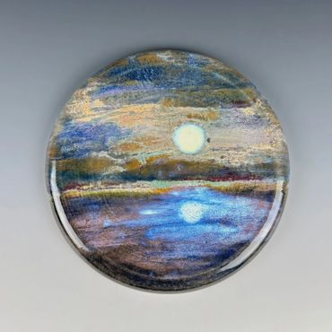 Round artwork depicting a serene moonlit sky over calm water.