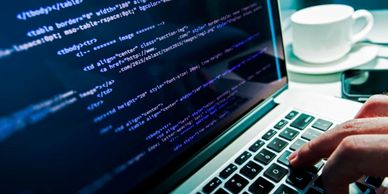 Person coding on a laptop with a cup of coffee nearby.