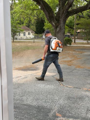 Man using a backpack leaf blower outside on a pavement.