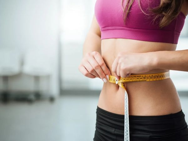 Woman measuring her waist with a tape measure.