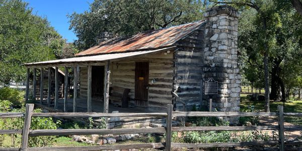 A scenic view of mountains under a clear blue sky with lush green trees in the foreground.