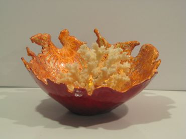 Gourd bowl with metallic coral colored interior and a piece of ivory coral in the center