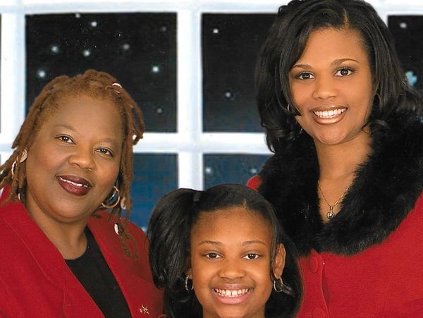Three smiling females posing indoors in red clothing.