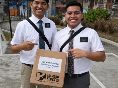 Two men in dress shirts pointing at a box.