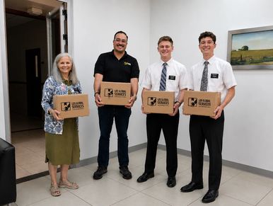 Four people holding boxes indoors.