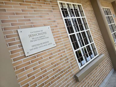 Sign on brick wall for The Church of Jesus Christ of Latter-day Saints mission office.