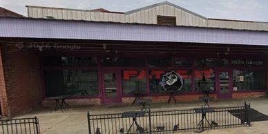 Front view of a building with a sign and tables outside.