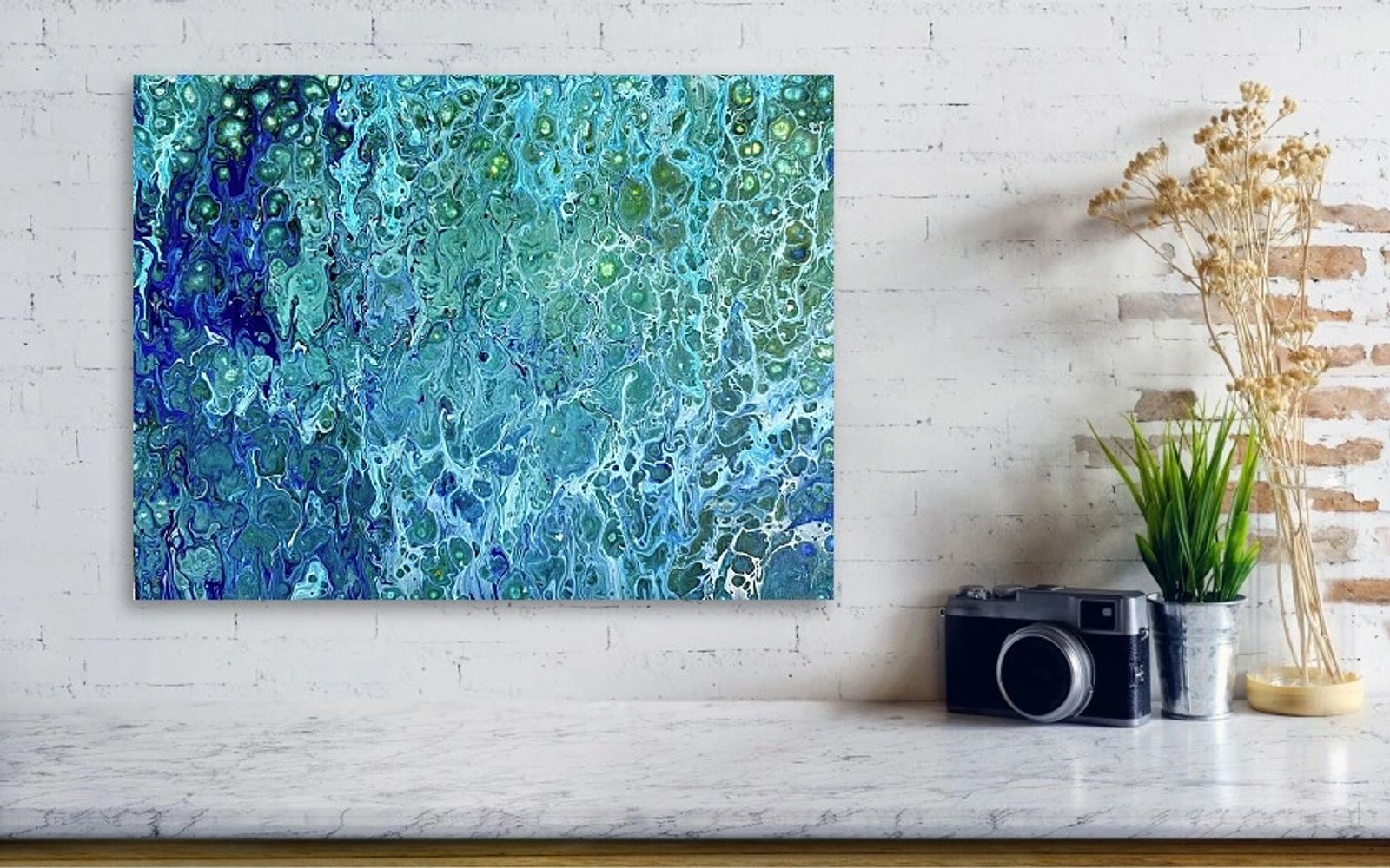 Abstract blue and green fluid art on a wall above a marble surface.