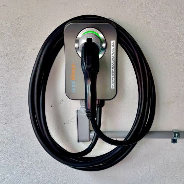 Electric vehicle charging station mounted on a wall with coiled cable.