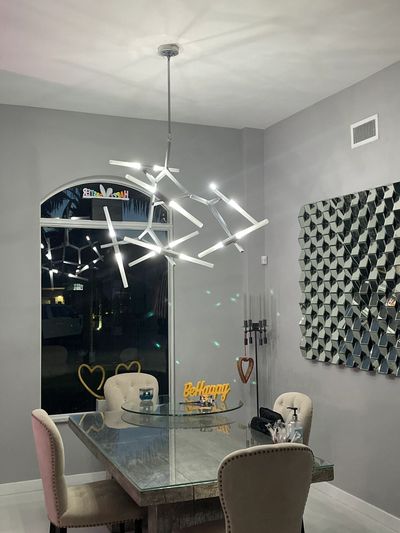 Modern dining room with geometric chandelier and glass table.