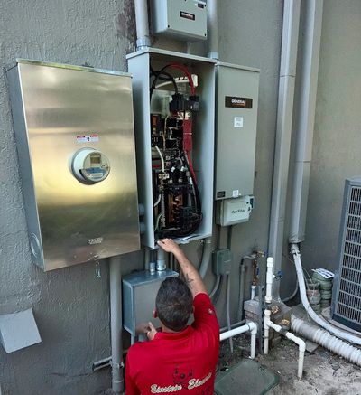 Technician inspecting an open electrical panel outdoors.