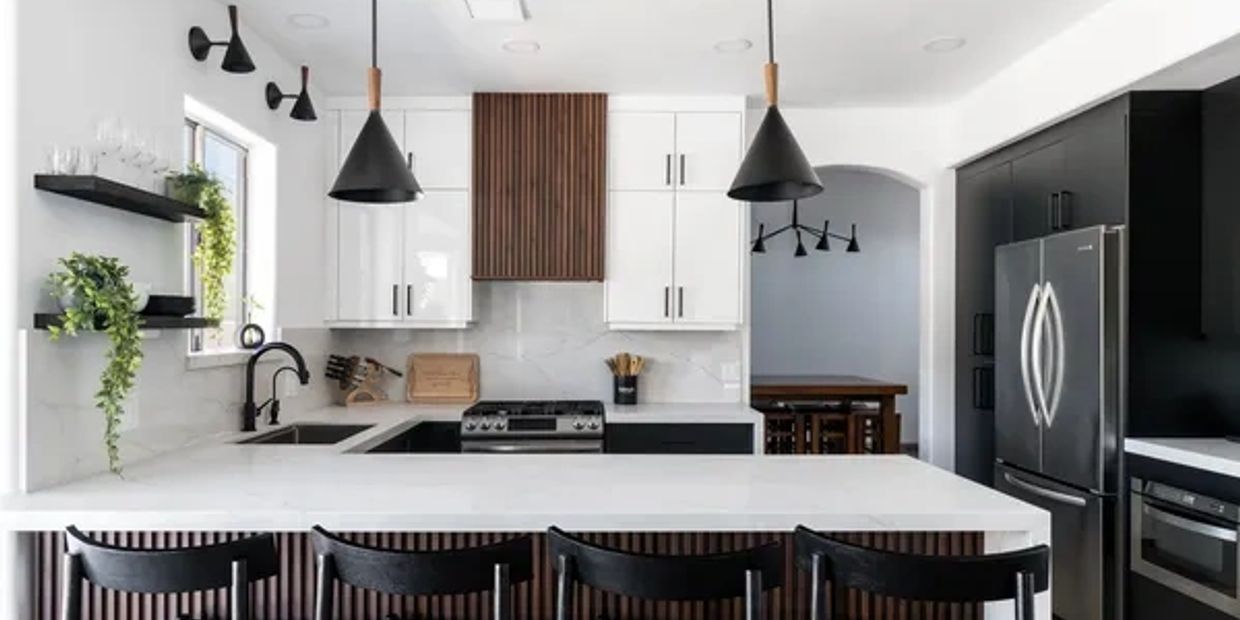 Modern white and black kitchen with wooden accents and plants.