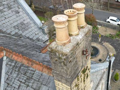 Old chimney with multiple clay pots on a rooftop of a historic building.