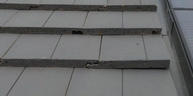 Damaged roof tiles with visible cracked interlocking channel on a new roof.