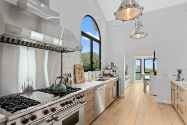 Modern kitchen with large window and wooden floors.
