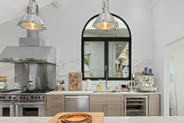 Modern kitchen with stainless steel appliances and large arched window.