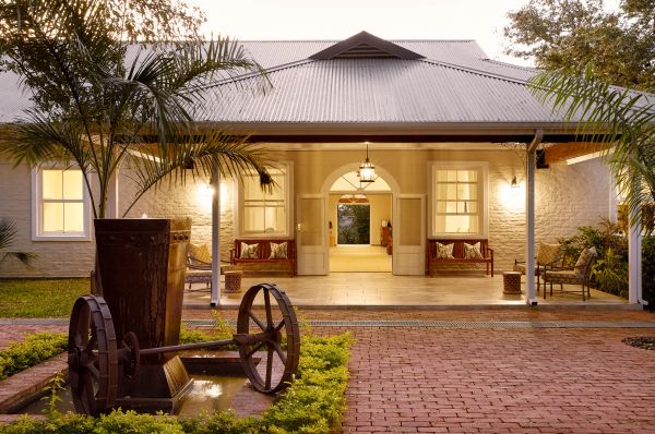 Cozy illuminated porch with seating and greenery at dusk.
