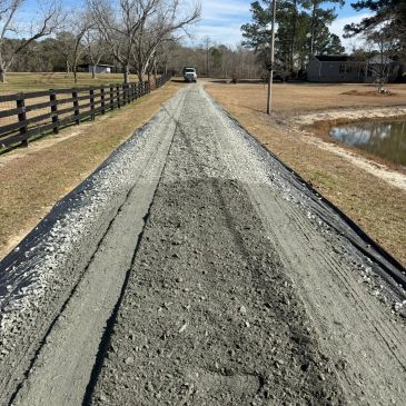 A gravel driveway under construction with a truck in the distance.