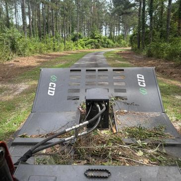 Forestry equipment clearing a path through a wooded area.