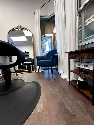 Cozy salon corner with a blue armchair and ornate mirror.