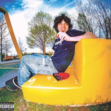 A young man sitting on a bright yellow playground structure outdoors.