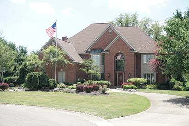 Large brick house with a well-maintained lawn and American flag.