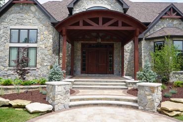 Stone house exterior with wooden entrance and large windows.