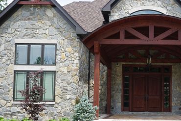 Stone house exterior with wooden entrance and large windows.