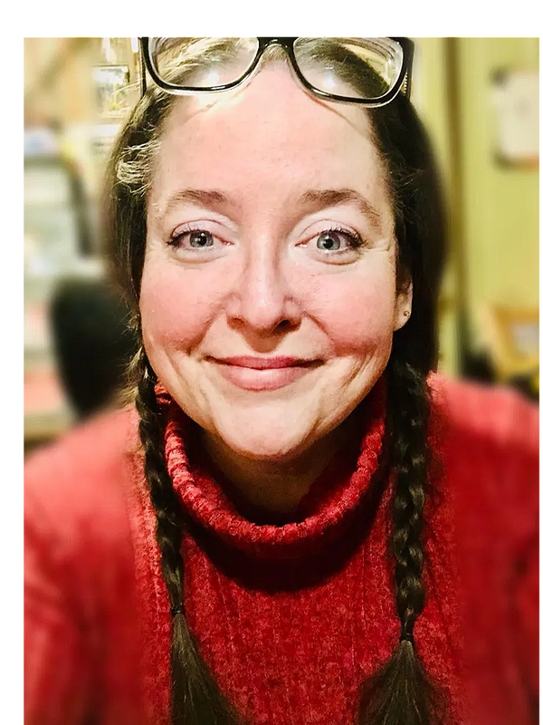 Photo of artist, Dannielle Vincent smiling wearing a red sweater and her glasses are on her forehead