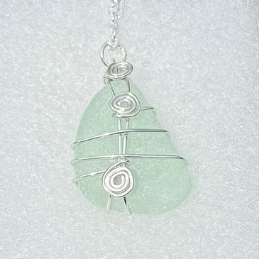 a piece of aqua coloured seaglass in the shape of a tear & silver wire wrapped wire with 3 spirals