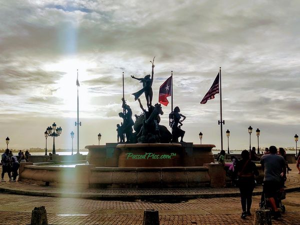 Raíces Fountain in San Juan in Puerto Rico with flags blowing in the wind near the Atlantic Ocean.