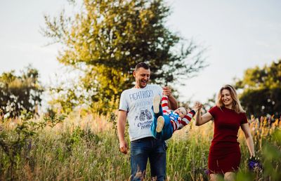 Parents swinging their child outdoors.