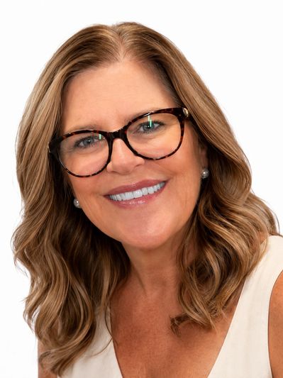 Smiling woman with wavy hair and glasses.