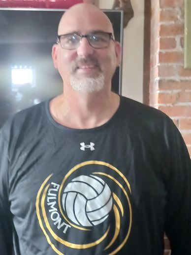 Man wearing glasses and a volleyball sport shirt indoors.