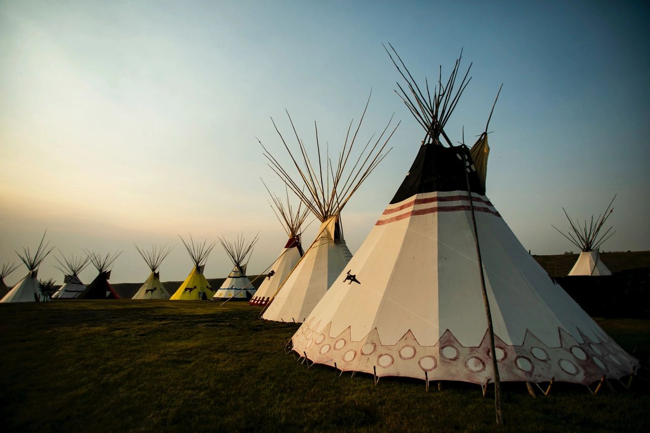 A row of colorful Native American teepees under a calm sky.