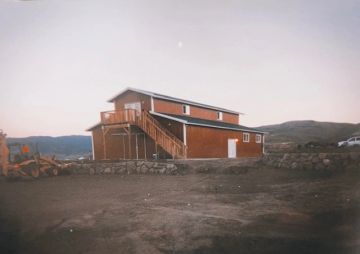 A rustic two-story barn with stairs outside in a rural setting.