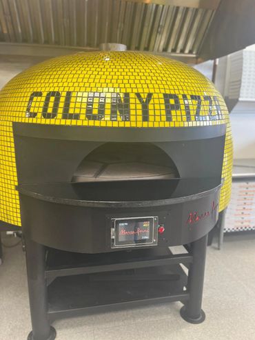 Yellow mosaic pizza oven with 'COLONY PIZZA' text.