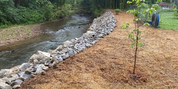 We helped with this eroding creek bank by adding stabilization in the form of geotextile fabric, bou