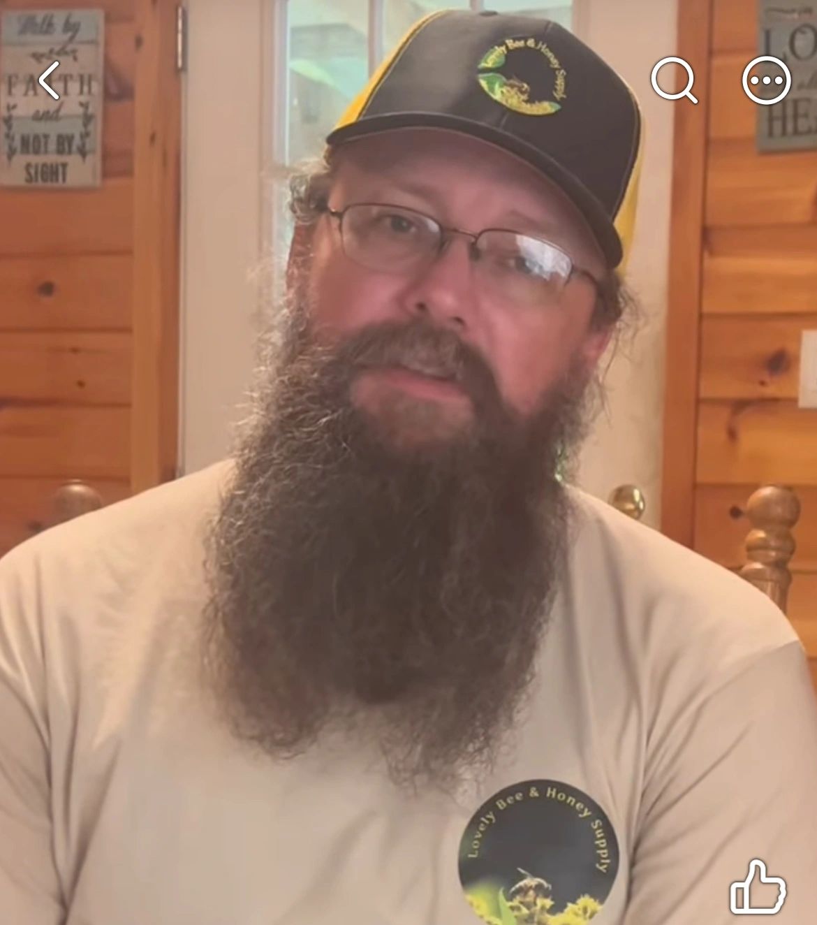 Bearded man wearing a cap and glasses indoors.