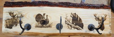 Wooden coat rack with wildlife engravings and metal hooks.