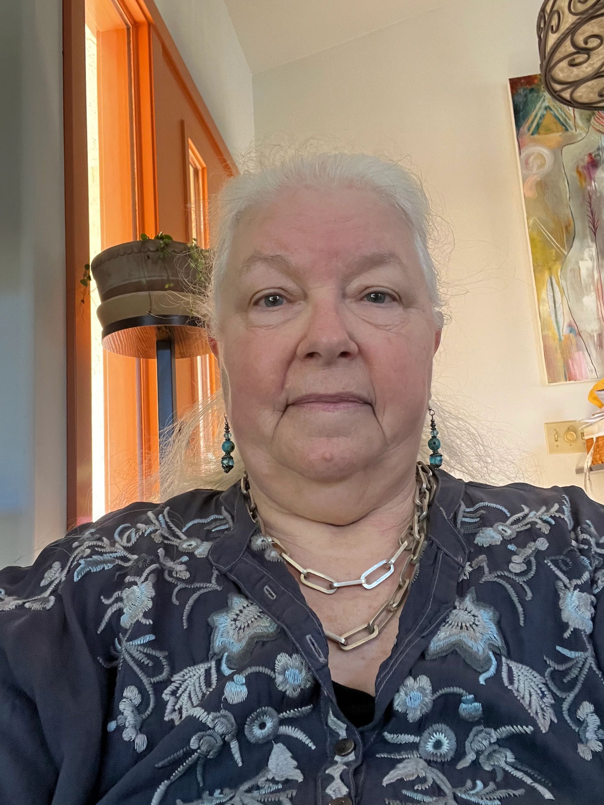 Portrait of an elderly woman with blue floral blouse and jewelry.